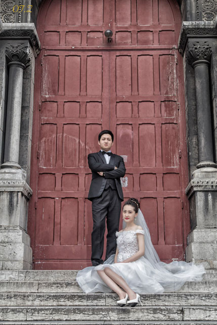 Wedding couple posed on stone steps before a red church door