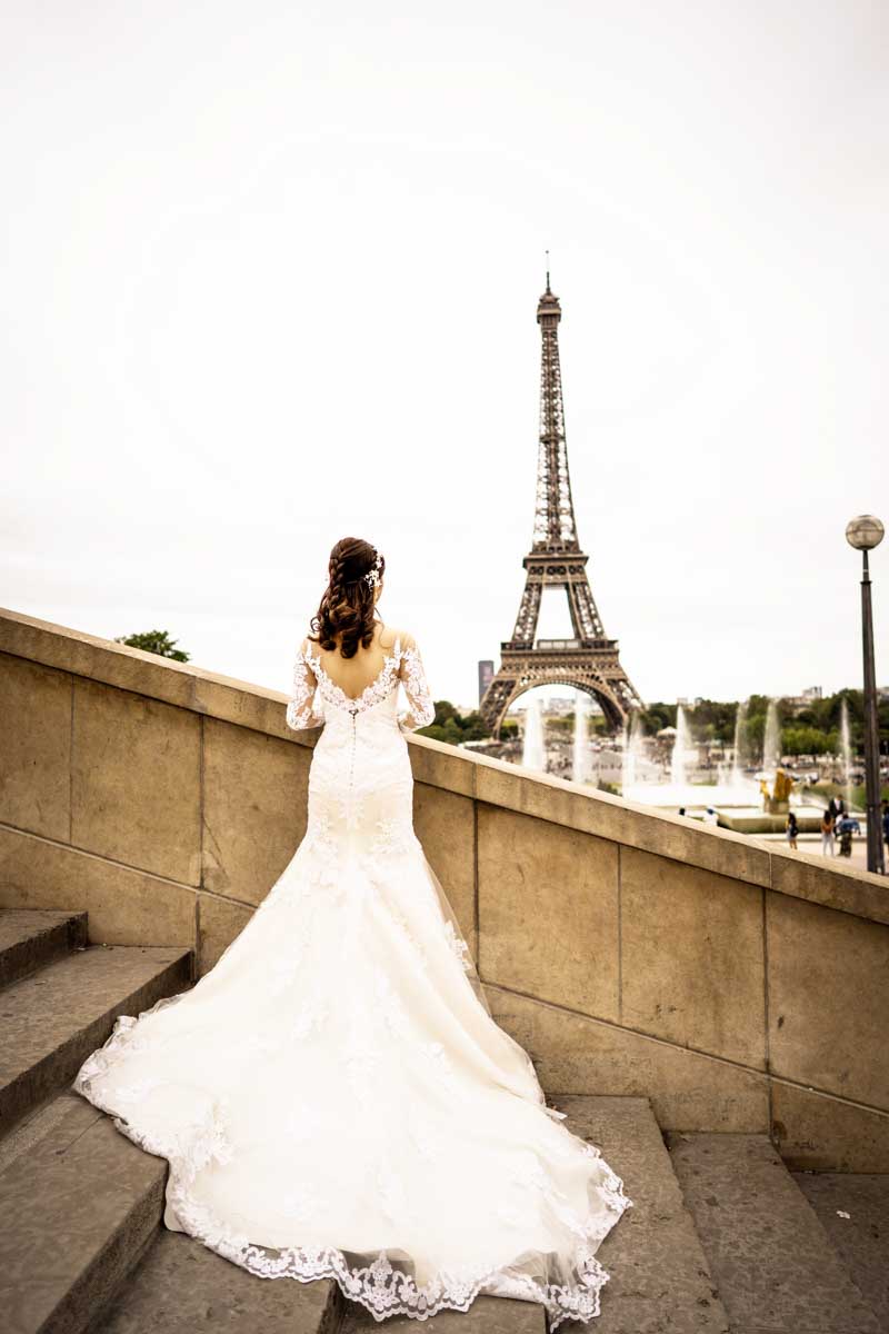 Bride in her wedding gown looking toward the Eiffel Tower