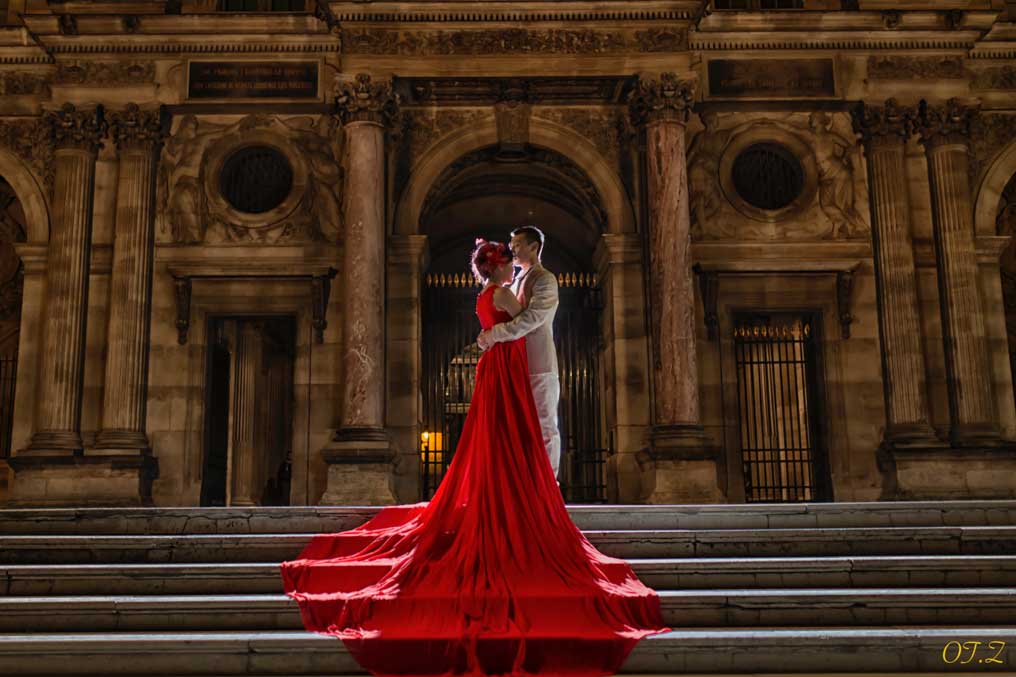 Woman in a red gown on the steps of a Paris monument at night